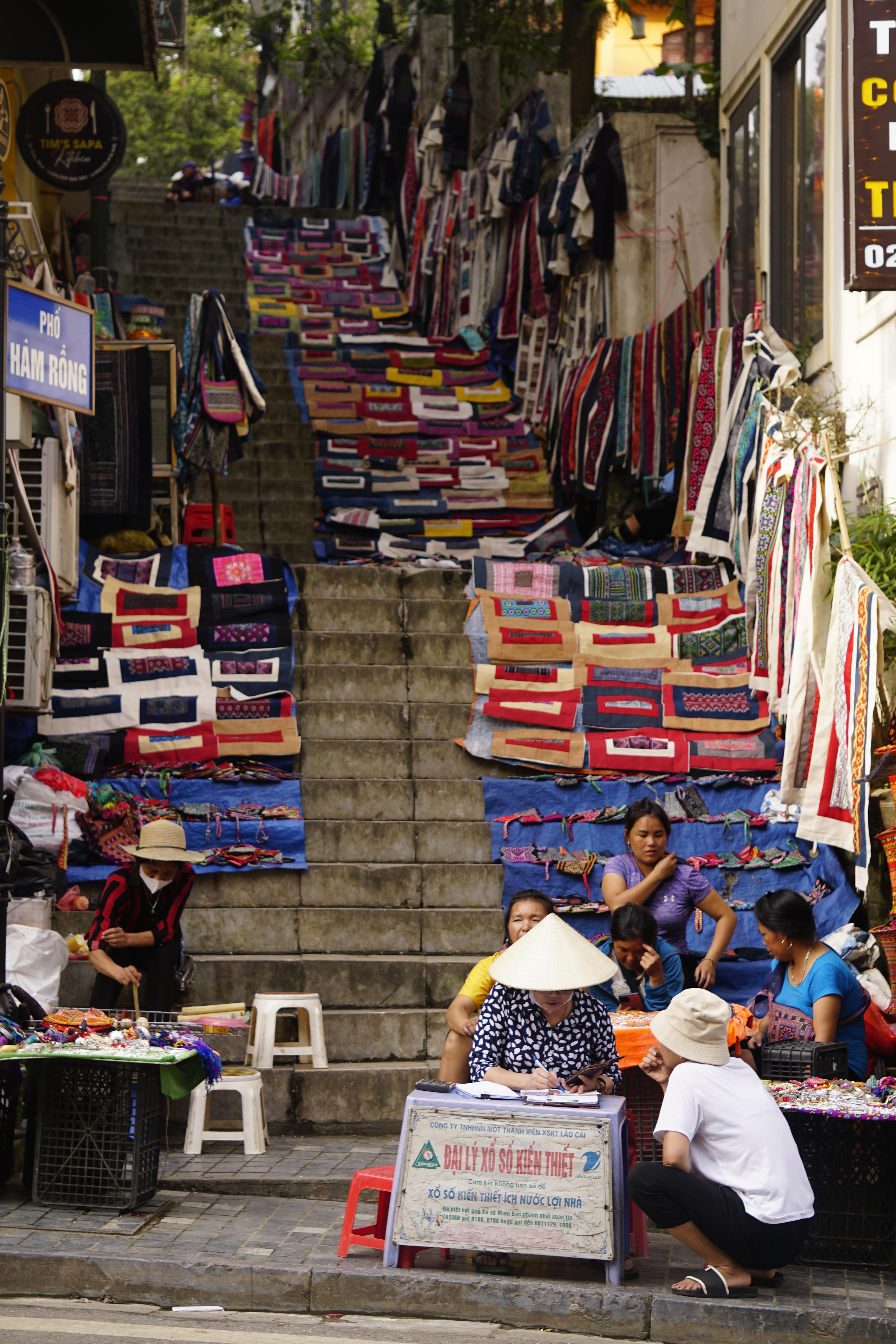 Brightly coloured woven textiles laid out by women at a hill-country market