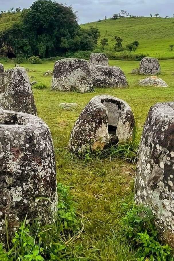 Large ancient stone jars lying in a green meadow