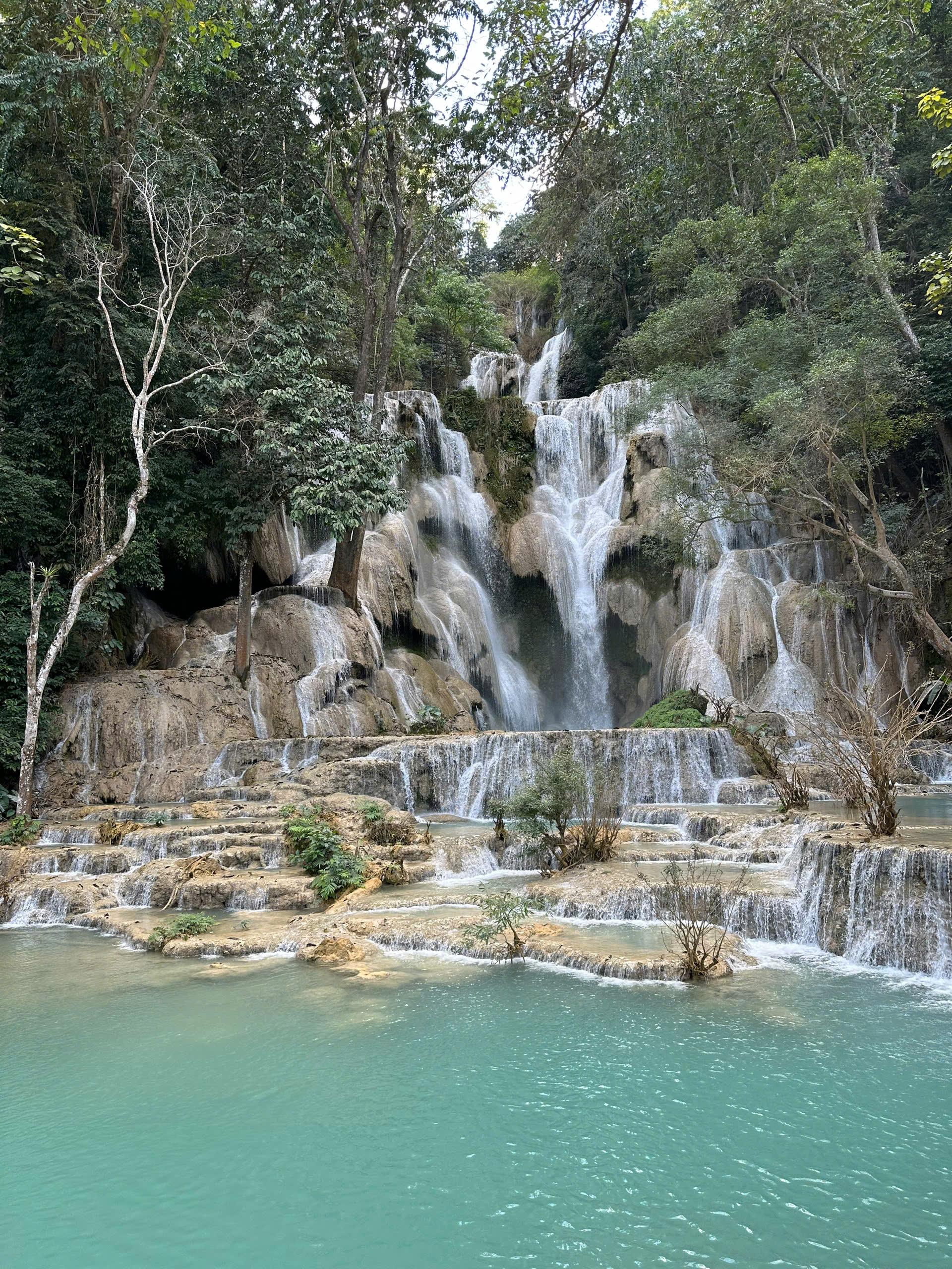 A wide tiered waterfall spilling into turquoise pools