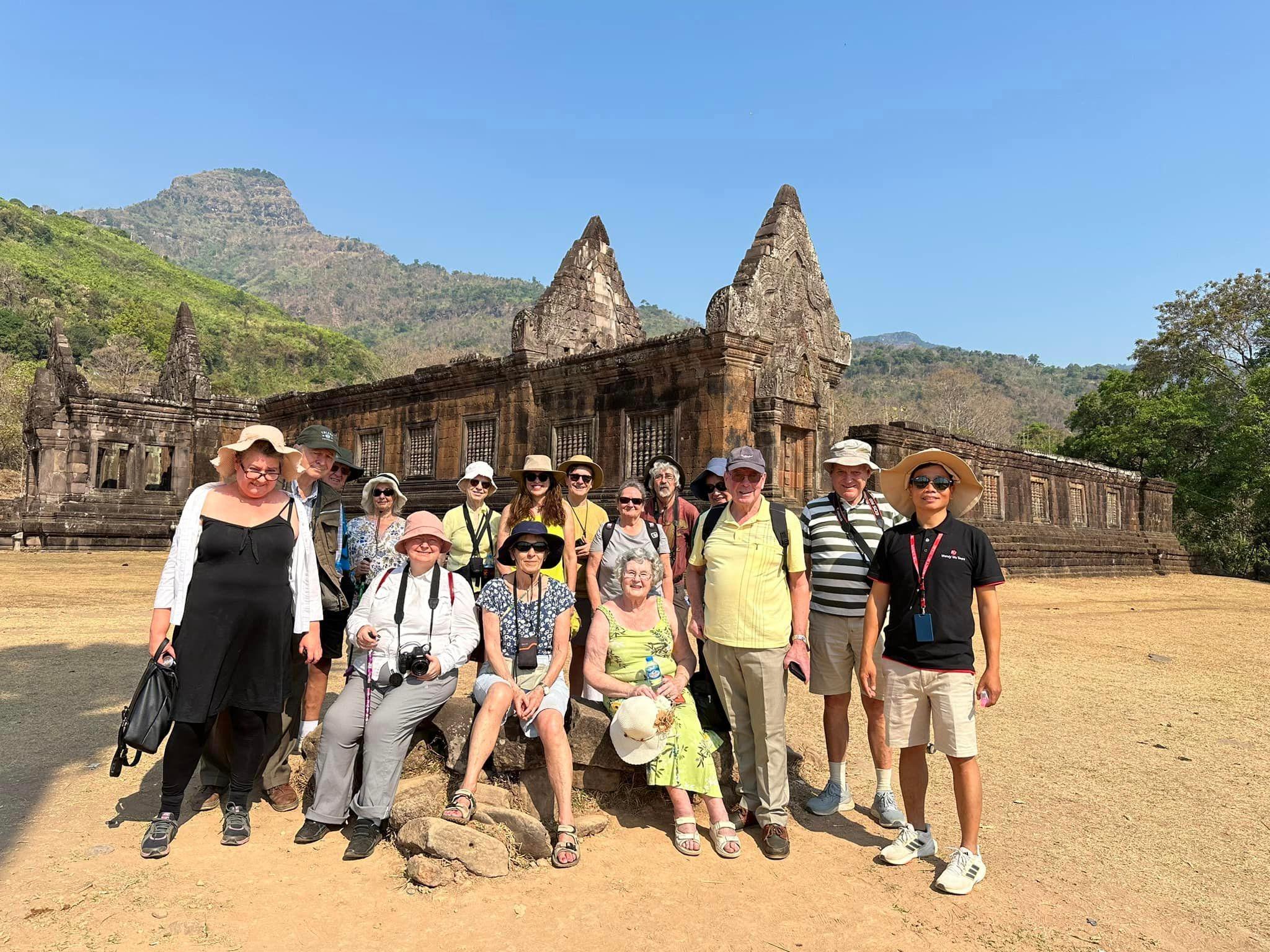 A group of travellers standing together in front of an ancient stone temple