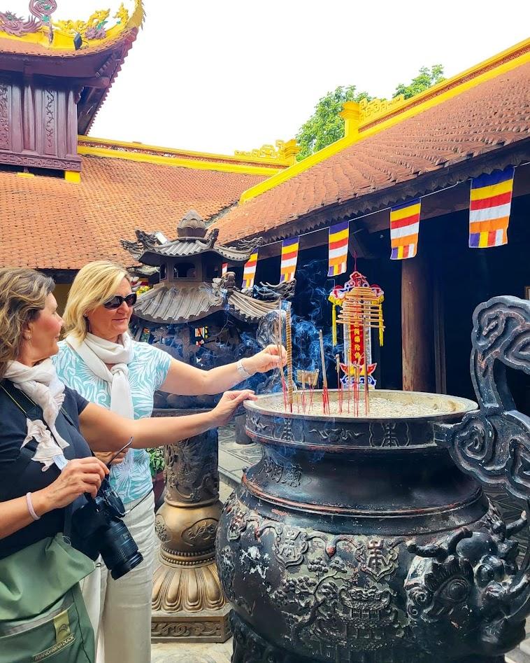 Due viaggiatrici accendono l'incenso nel braciere di bronzo di una pagoda