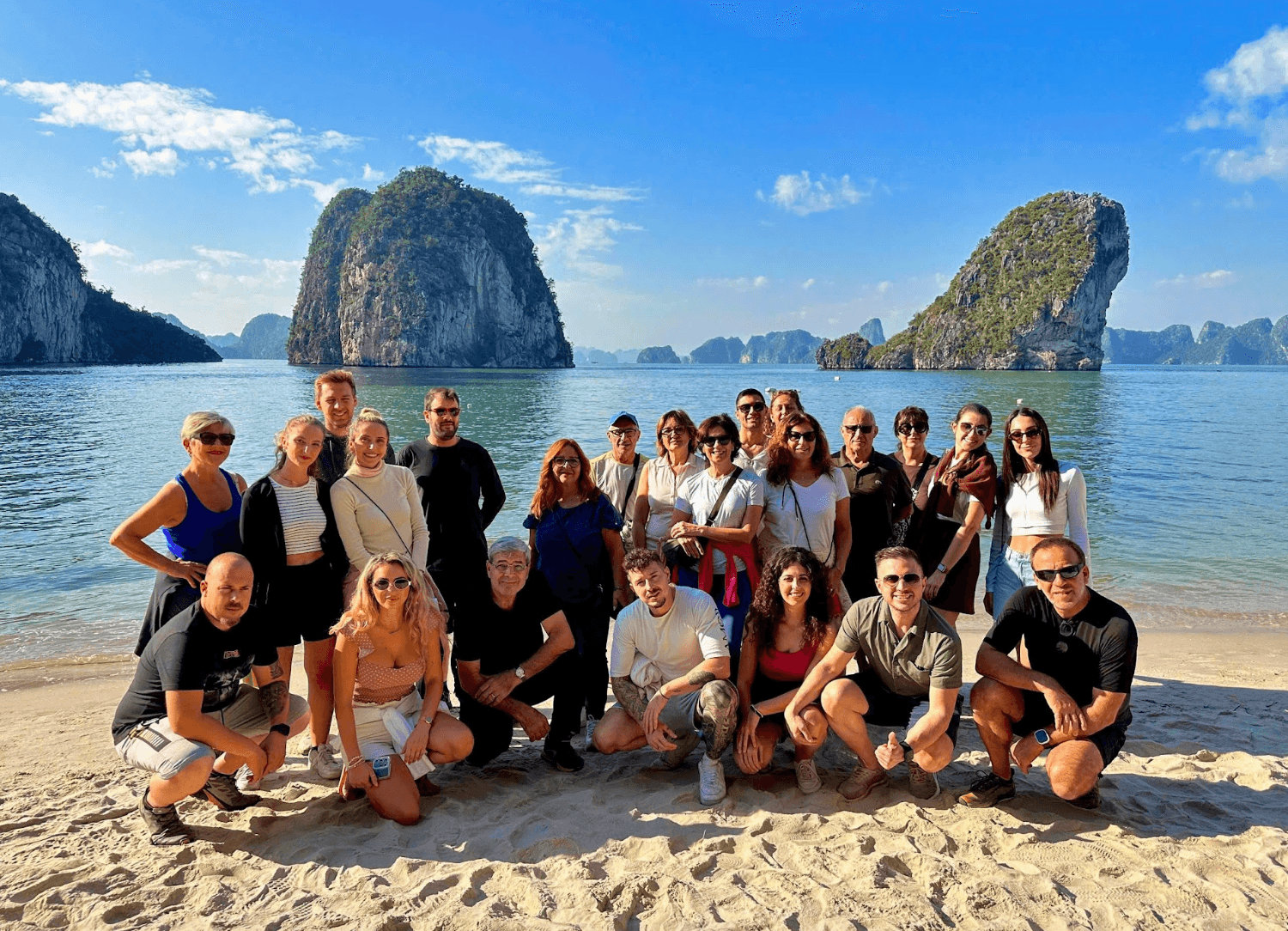 Gruppo sulla spiaggia con i faraglioni della baia sullo sfondo