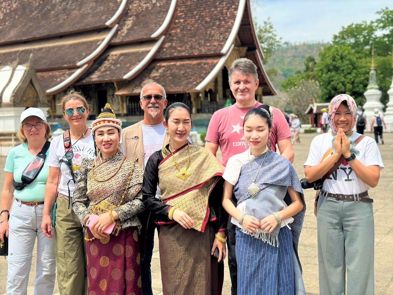 Gruppo con ragazze in abito tradizionale laotiano davanti a un tempio di Luang Prabang