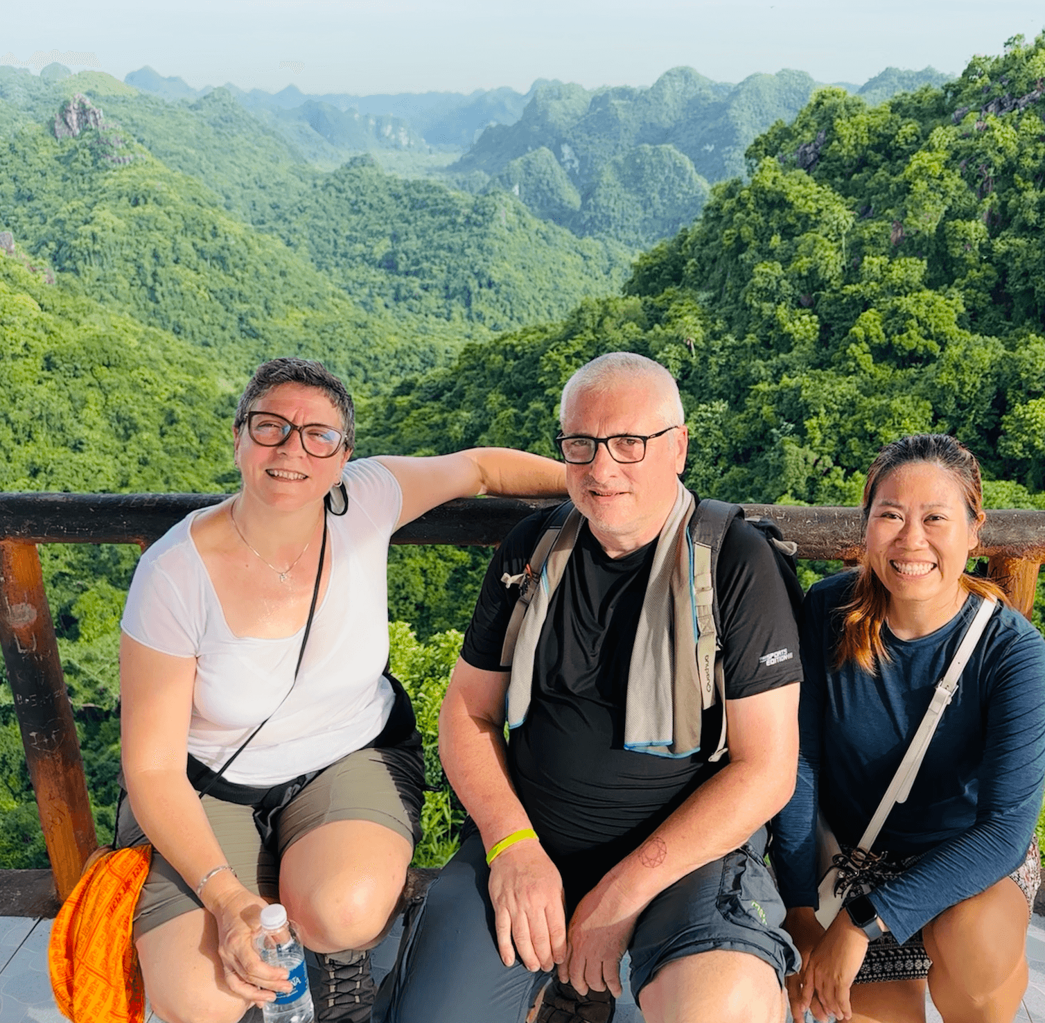 Tre viaggiatori su una terrazza panoramica davanti alle montagne carsiche coperte di foresta