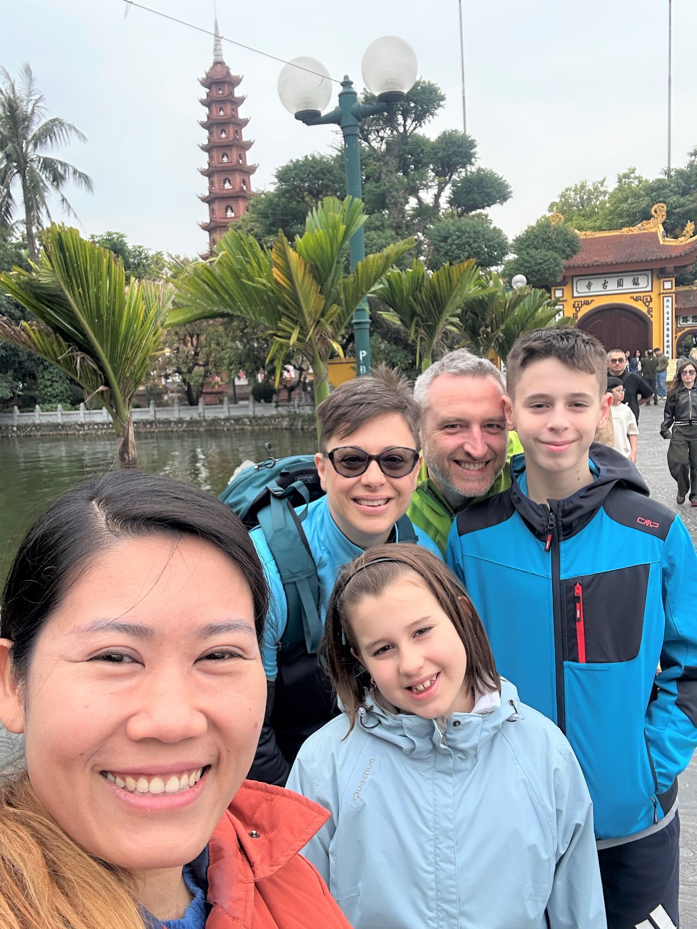 Selfie di una famiglia con la guida davanti alla pagoda sul lago, ad Hanoi
