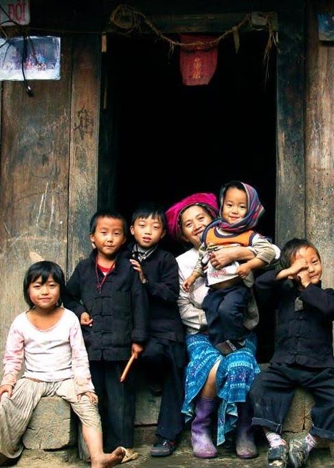 Children and a woman in traditional dress sitting together in a wooden doorway