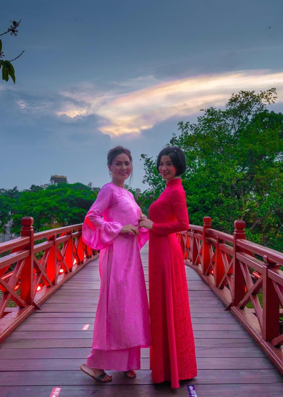 Travellers in ao dai on a red bridge at sunset in Indochina