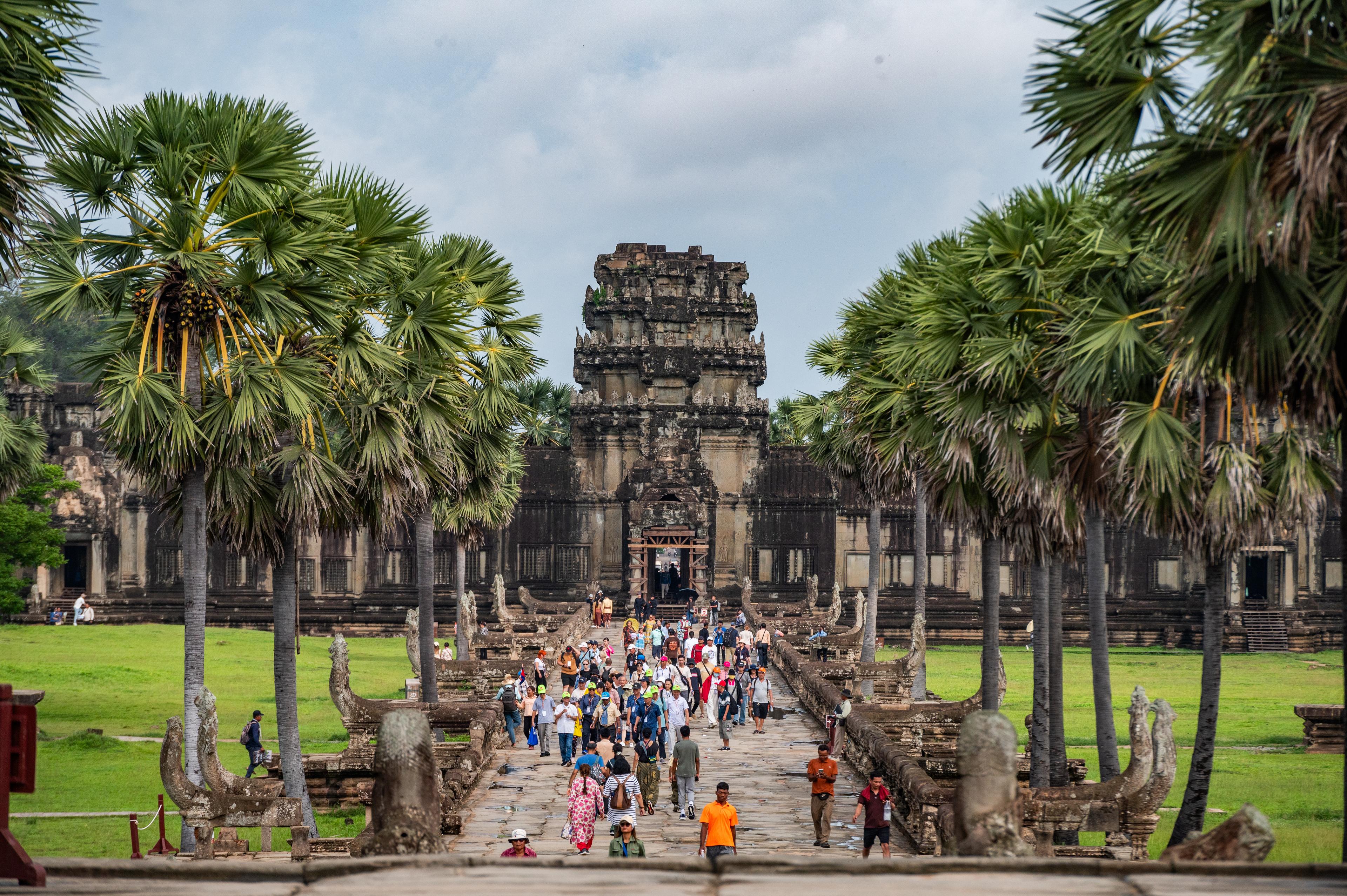 Visitors crossing the palm-lined causeway towards a temple gate