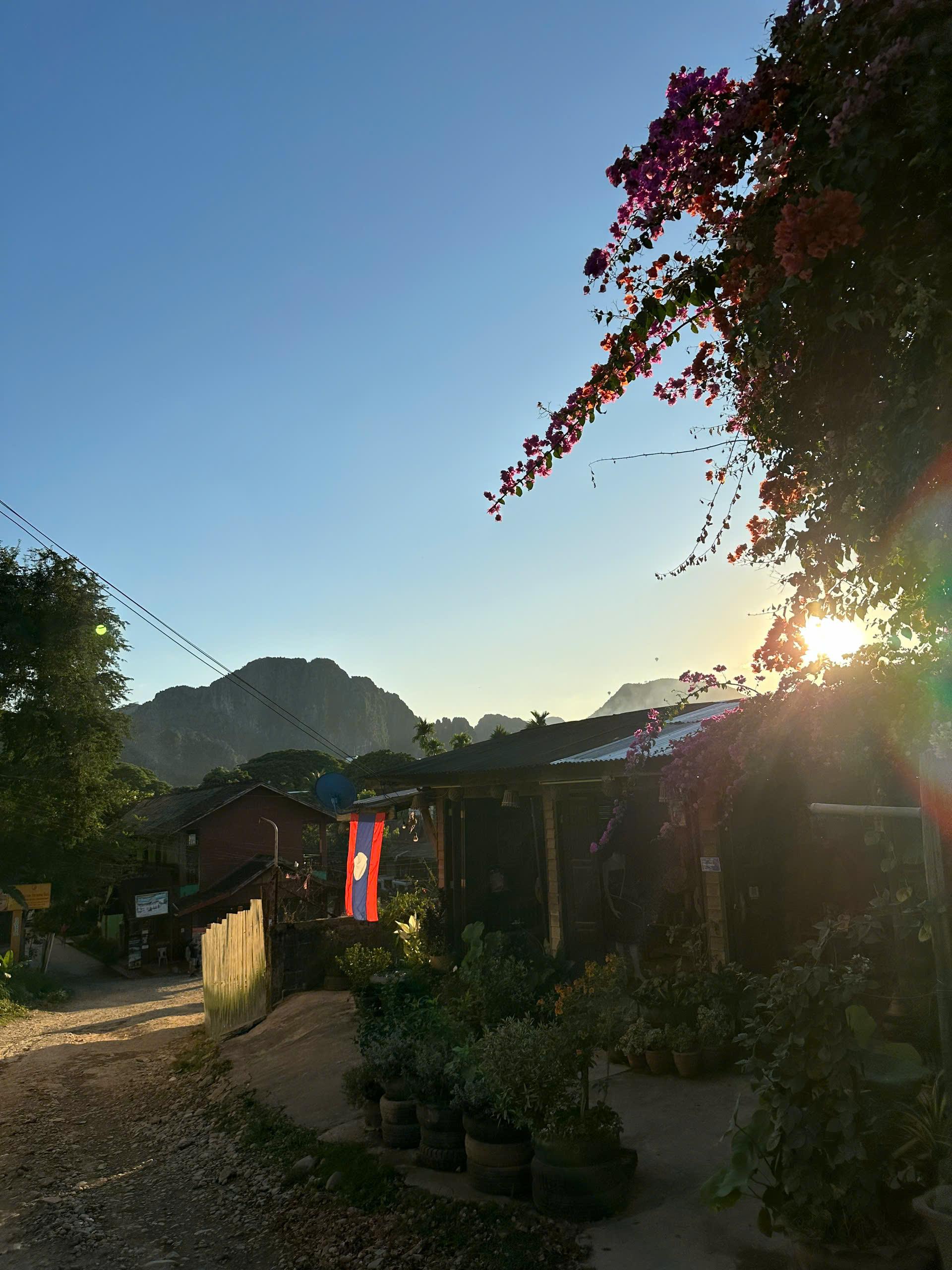 A village street at sunset with limestone peaks behind the rooftops