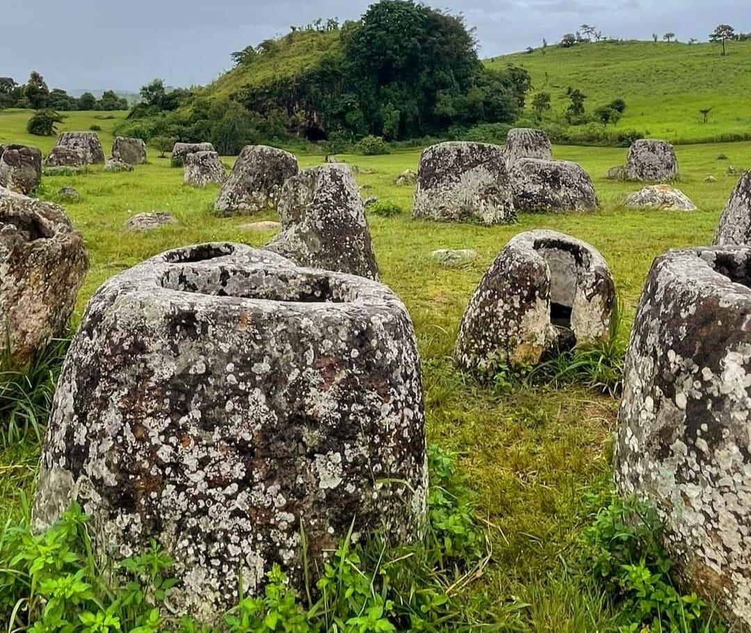 A field of ancient stone jars under a blue sky